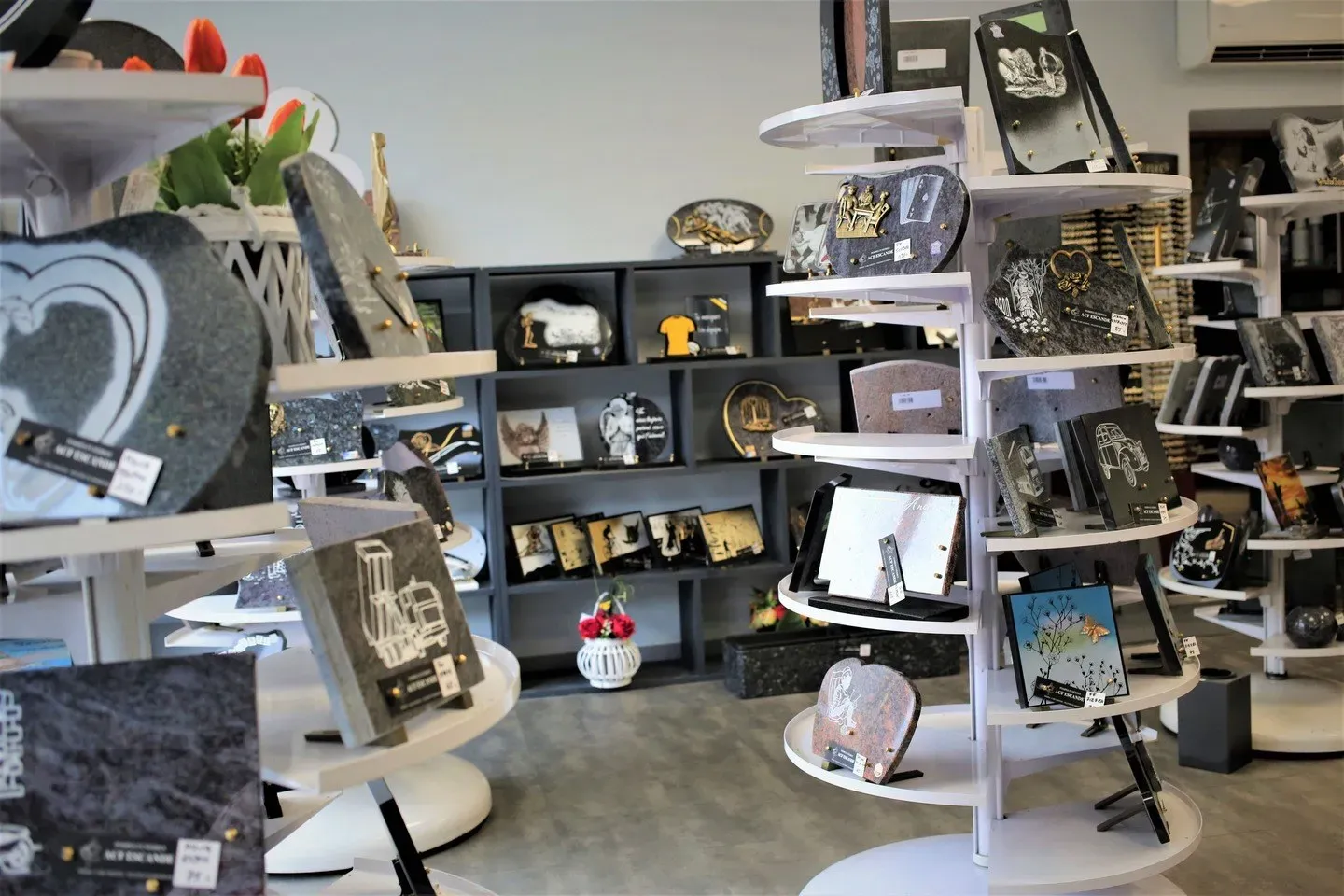Large choix de plaques funéraires gravées exposées sur des présentoirs.
