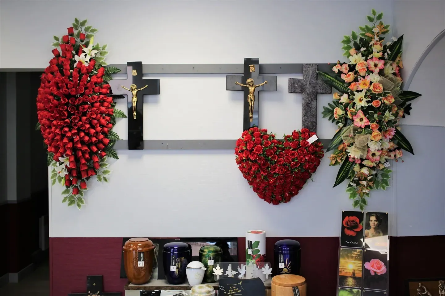 Compositions florales, croix religieuses et urnes funéraires exposées en magasin.