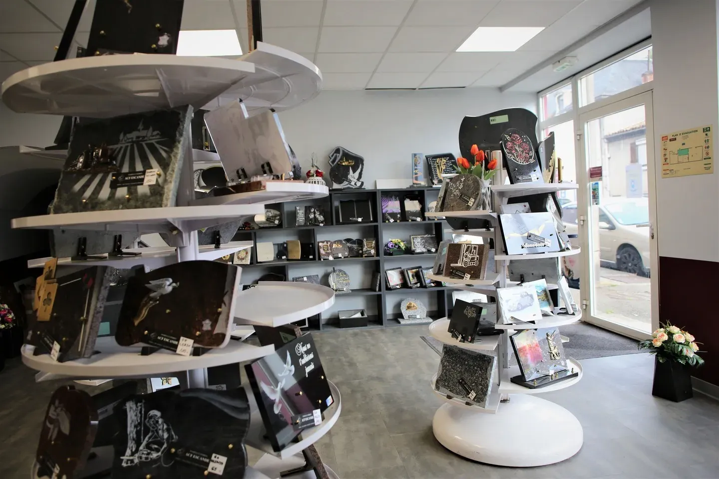 Plaques funéraires sur présentoirs ronds dans un magasin d'articles de deuil.