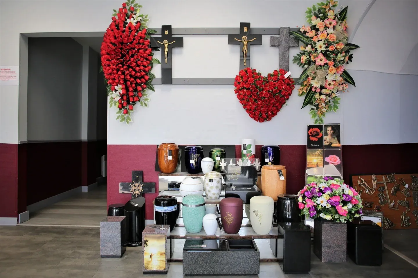 Urnes funéraires, fleurs et croix exposées dans un magasin spécialisé.